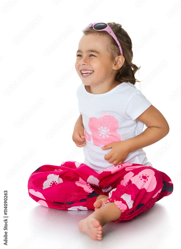 Joyful barefoot little girl in pink glasses sitting on the floor - Isolated on white background Joyful barefoot little girl in pink glasses sitting on the floor - Isolated on white background
