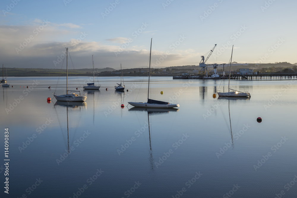 River Tamar at sunrise with boats and reflections , Devon and Cornwall Uk