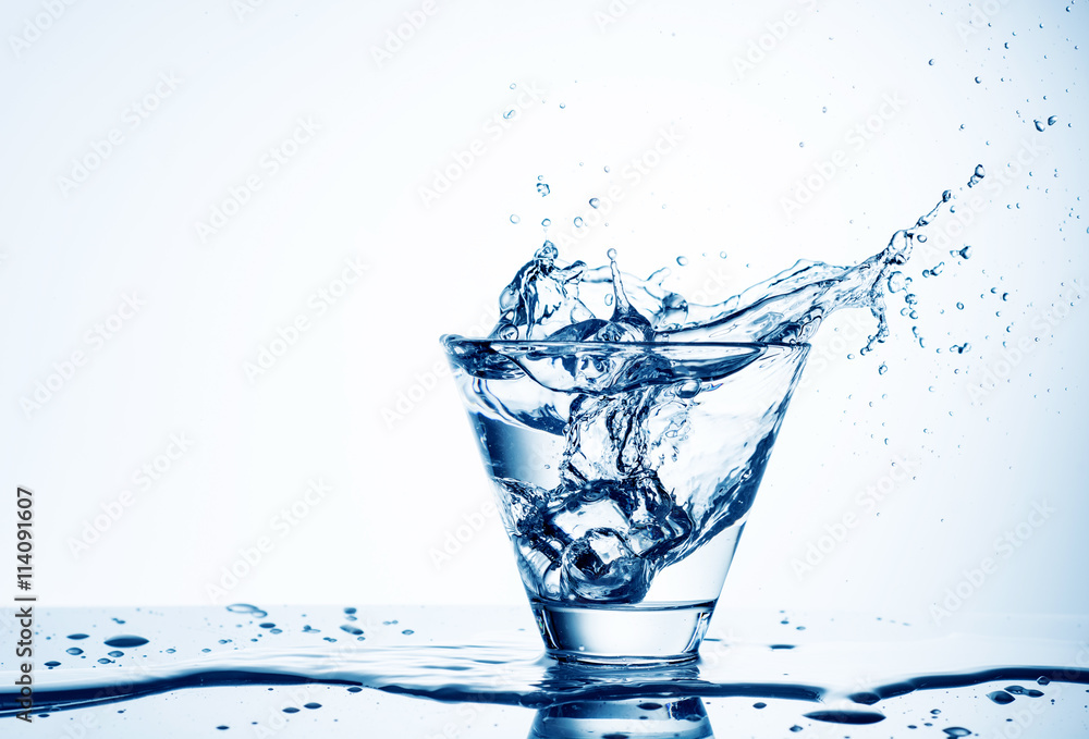Ice cubes splashing into glass of water, isolated on white Ice cubes splashing into glass of water, isolated on white