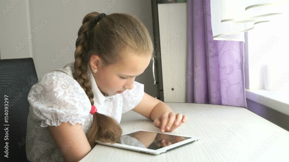 Schoolgirl uses a digital tablet computer at home Schoolgirl uses a digital tablet computer at home