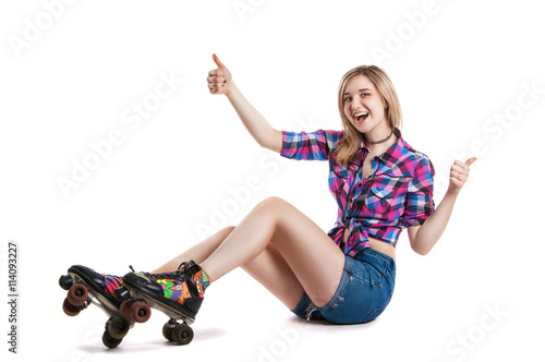 Joyful young girl in roller skates. A girl sits on the floor and laughs. It shows the gesture class.