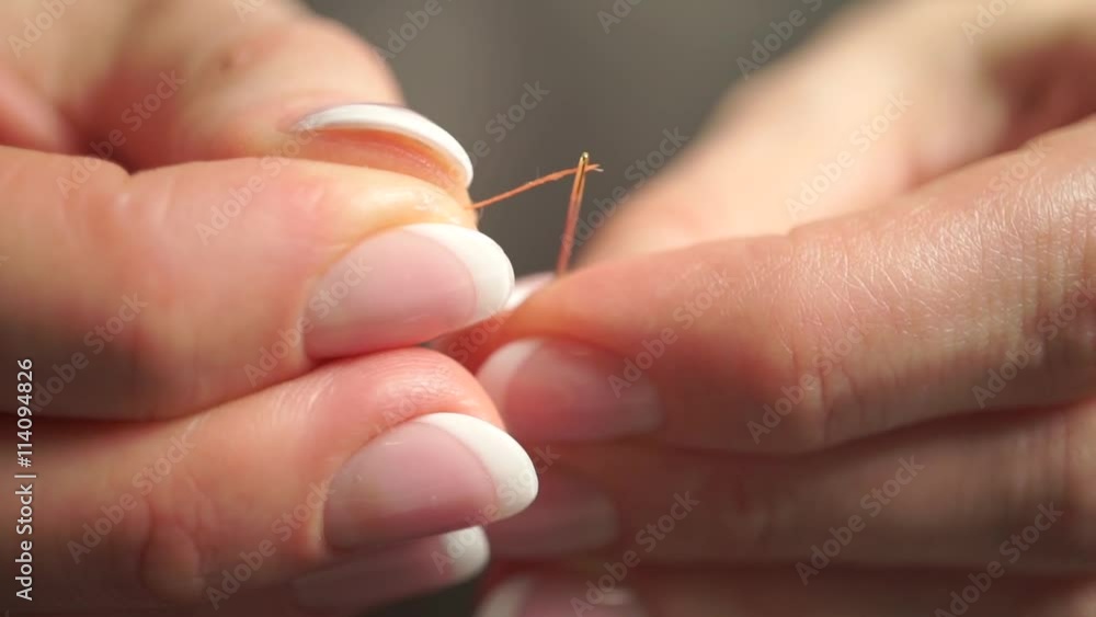 Threading a needle with an orange thread. Macro video with racking focus Threading a needle with an orange thread. Macro video with racking focus