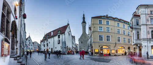 Crowded Tallinn Old town streets with Town Hall in the evening. Panoramic montage from 7 HDR images. Long exposure with motion blur