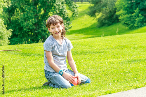 Adorable young child boy laying on the grass in the park. On war