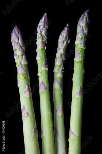 Raw asparagus on black background