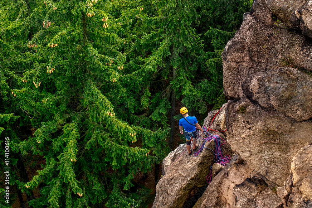 Fototapeta premium Men climbing vertical wall, on a background with trees, Poland