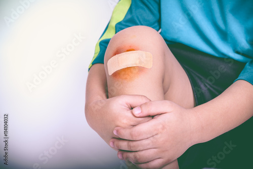 Athlete child injured. Child knee with a plaster and bruise. Vintage tone.