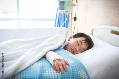 Asian boy lying on sickbed with saline intravenous (IV).  photo