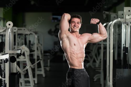 Muscular Man Flexing Muscles In Gym