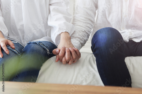 Young couple holding hands sitting on the sofa