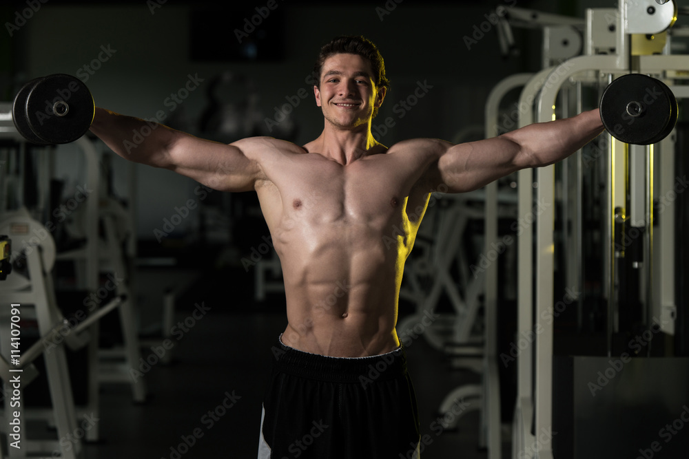 Young Man With Dumbbells Exercising Shoulders