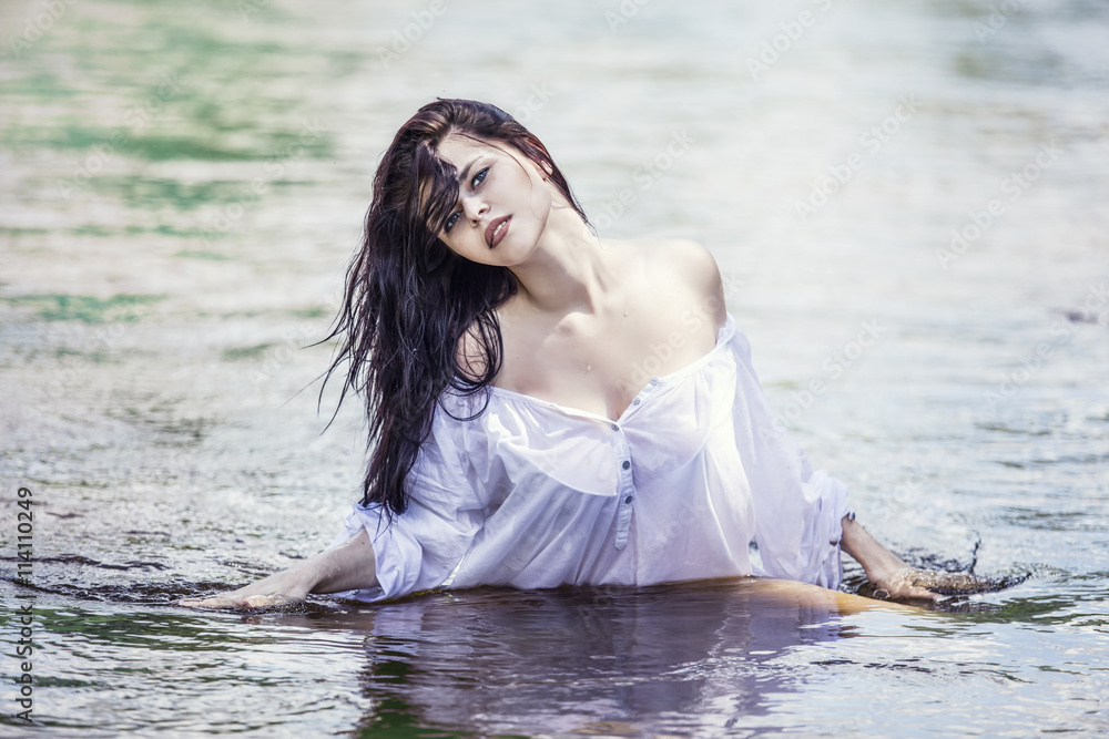 Fototapeta premium Young beautiful brunette woman enjoys the lake with clear water