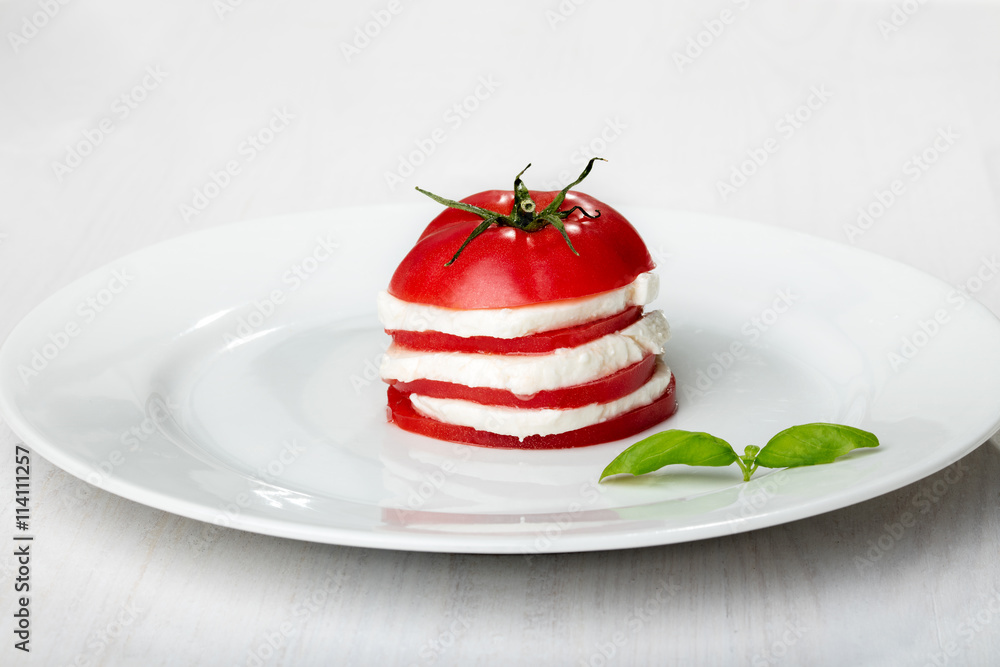 Tomato and mozzarella slices decorated with basil leaves Tomato and mozzarella slices decorated with basil leaves