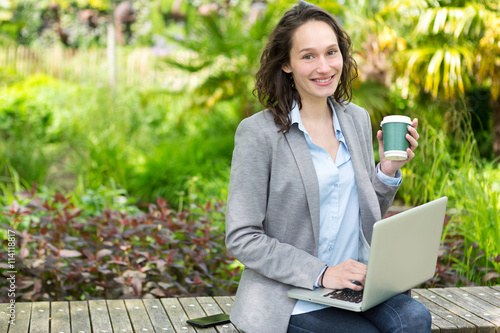 Young attractive business woman working at the park during a pau