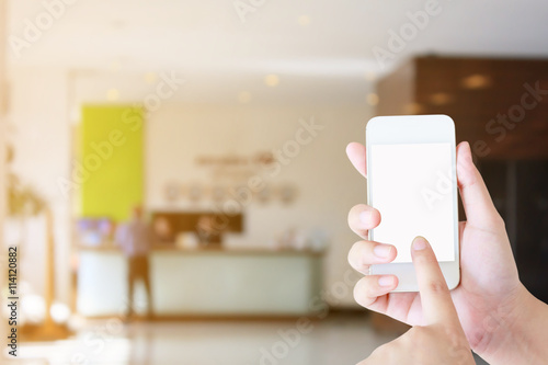 woman hand hold mobile smartphone with hotel lobby