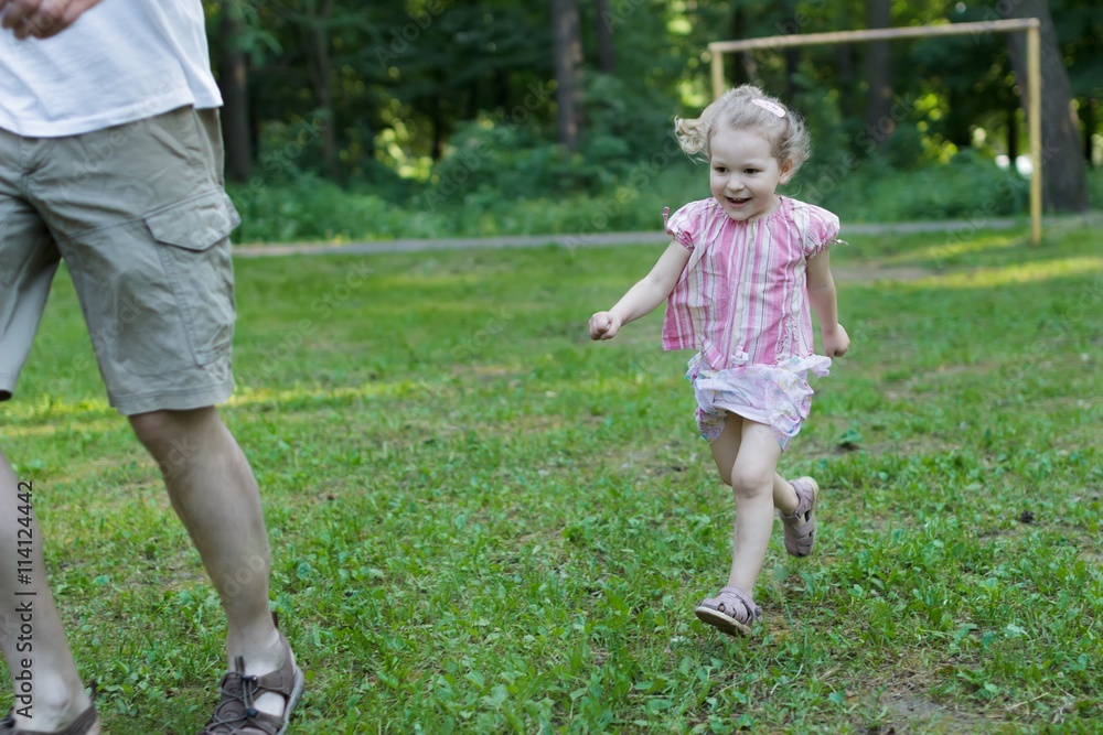 Cute little girl running after her father in summer park outdoors Cute little girl running after her father in summer park outdoors