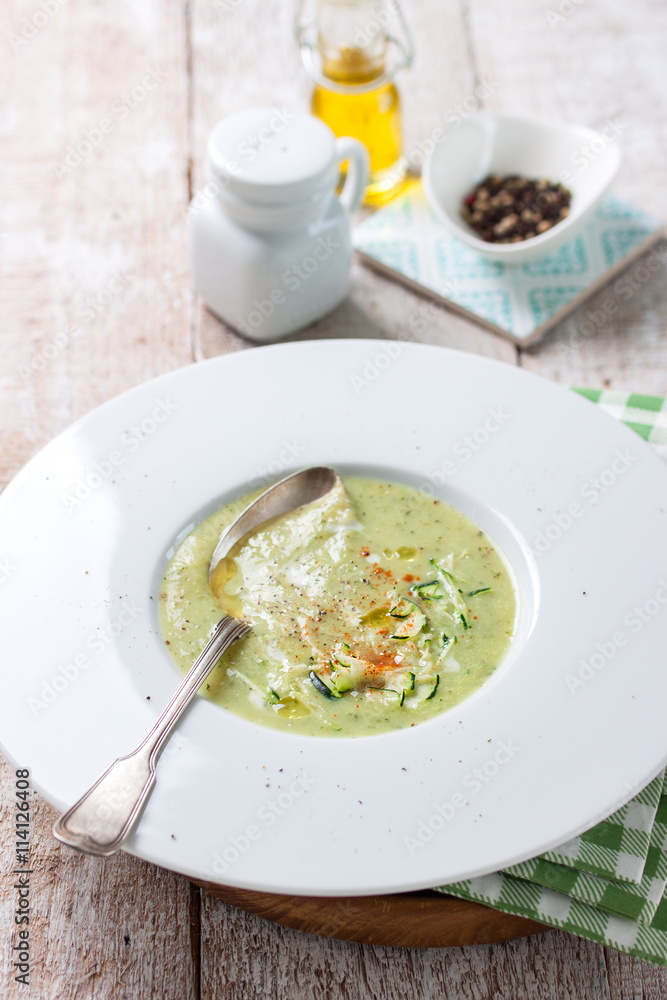 Zucchini vegetable creamy soup puree in a bowl on a wooden background, top view..