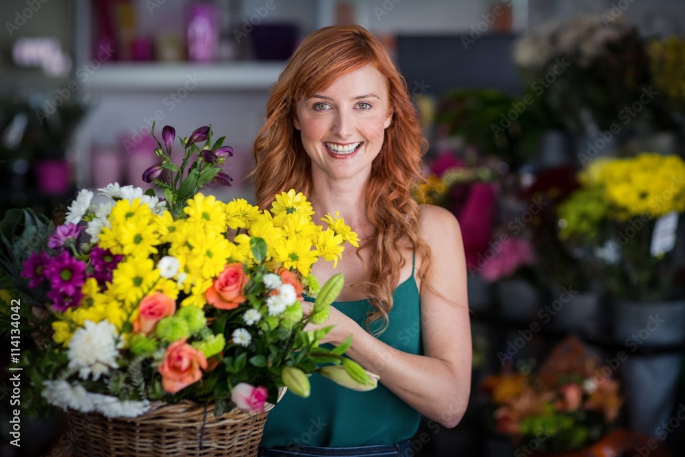 Happy female florist holding basket of flowers