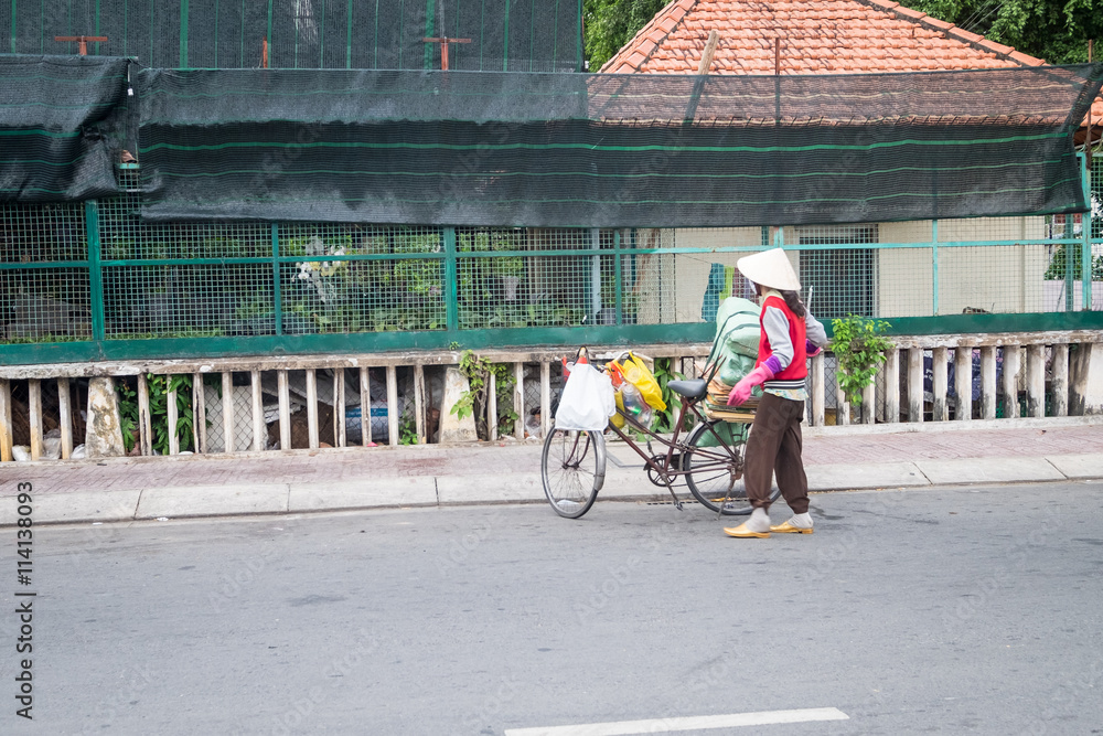 Obraz premium Ho Chi Minh, Vietnam - June 11, 2016: Woman worker collecting cartons for recycling in street city.