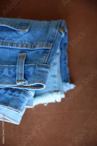 Fashionable stack of jeans, trouser, clothes on a texure backgro