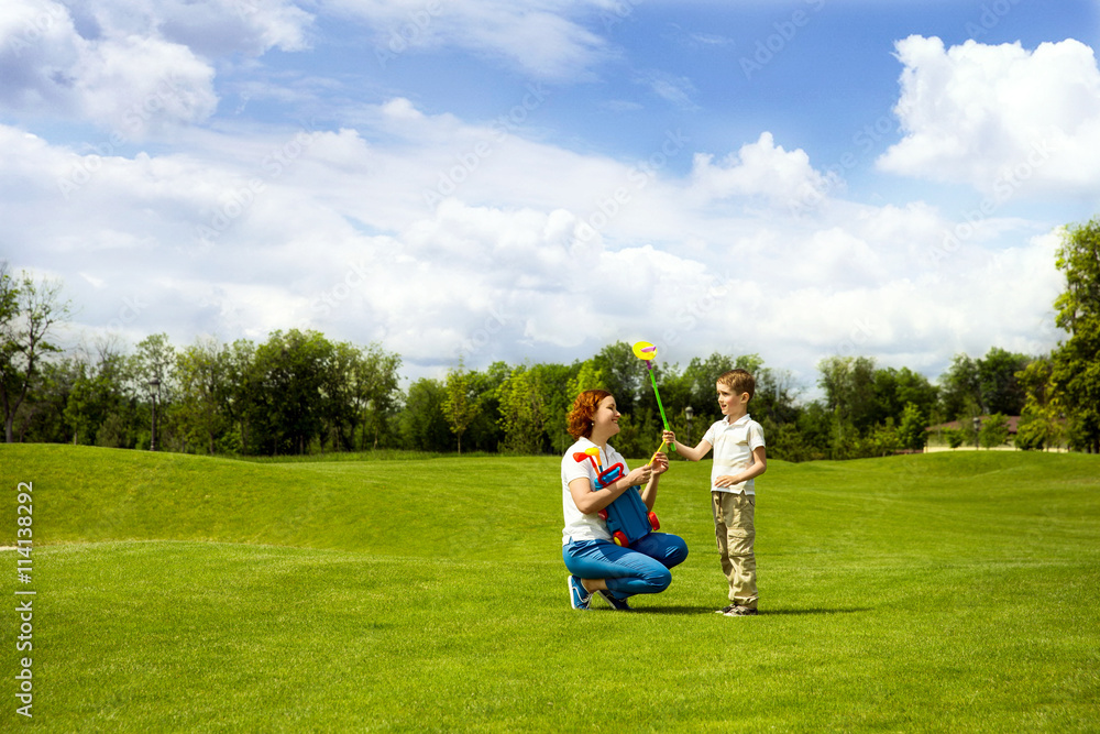 Mother teaching son to play golf
