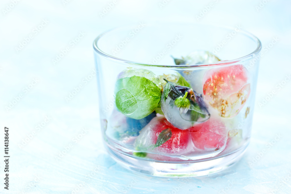 Fresh fruits and berry frozen in ice cubes on blue background Fresh fruits and berry frozen in ice cubes on blue background