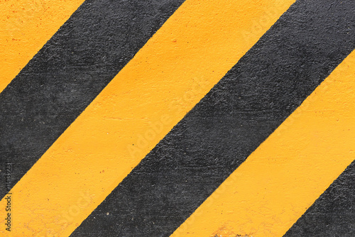 black and yellow striped caution sign on concrete wall background