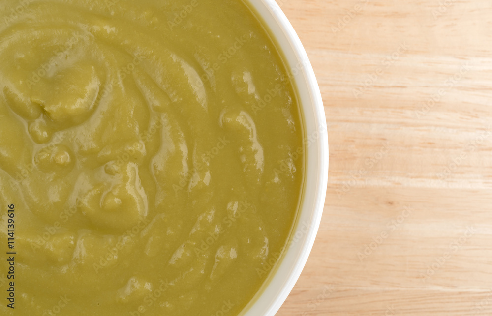 Bowl of green pea soup on a wood table top view. Bowl of green pea soup on a wood table top view.