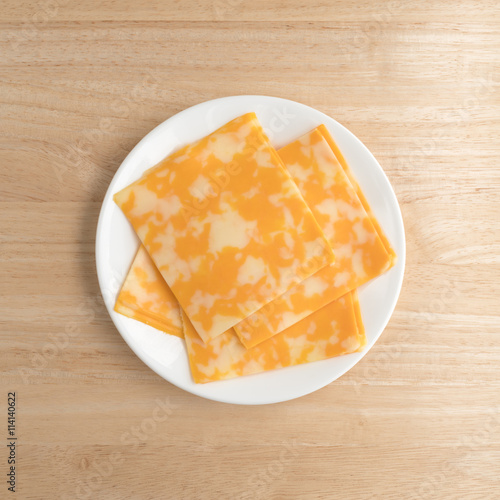 Colby-Jack cheese slices on a plate atop table top view.