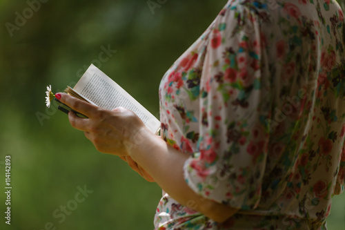 Woman's hand holding book in the park.