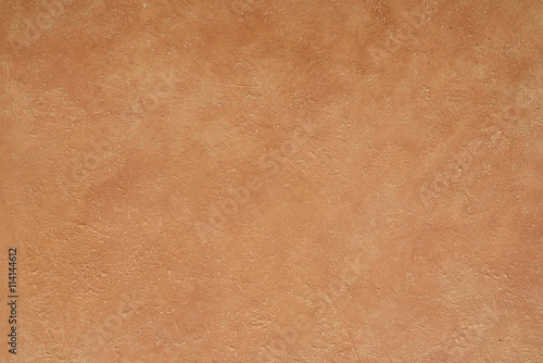 close up detail of rustic textured terracotta coloured stucco wall background