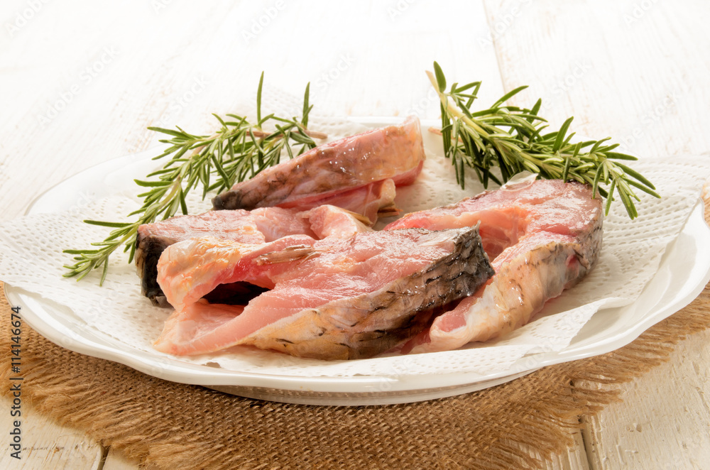 raw carp steak with paper kitchen towel and rosemary