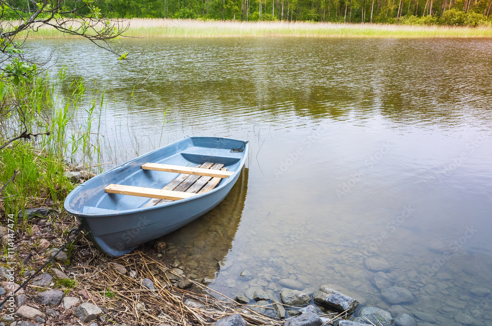Small rowboat lays on coast of still lake Small rowboat lays on coast of still lake