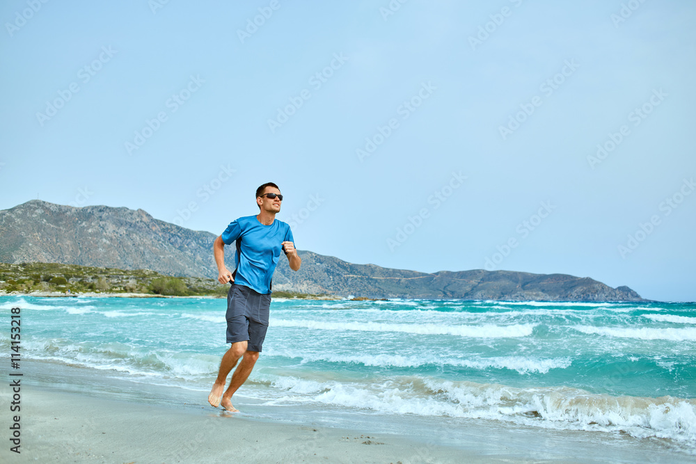 strong athletic man running on the beach along the sea front