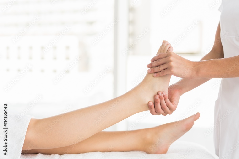 Midsection of masseur giving foot massage to woman Midsection of masseur giving foot massage to woman
