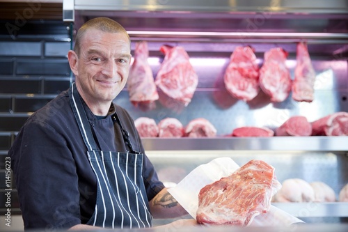 Portrait of butcher holding fresh meat in butchers shop