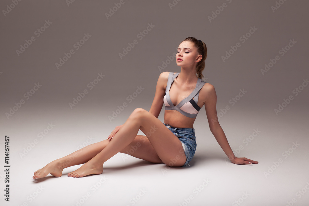 sexy woman in shorts and lingerie on a gray gradient background, aroused body