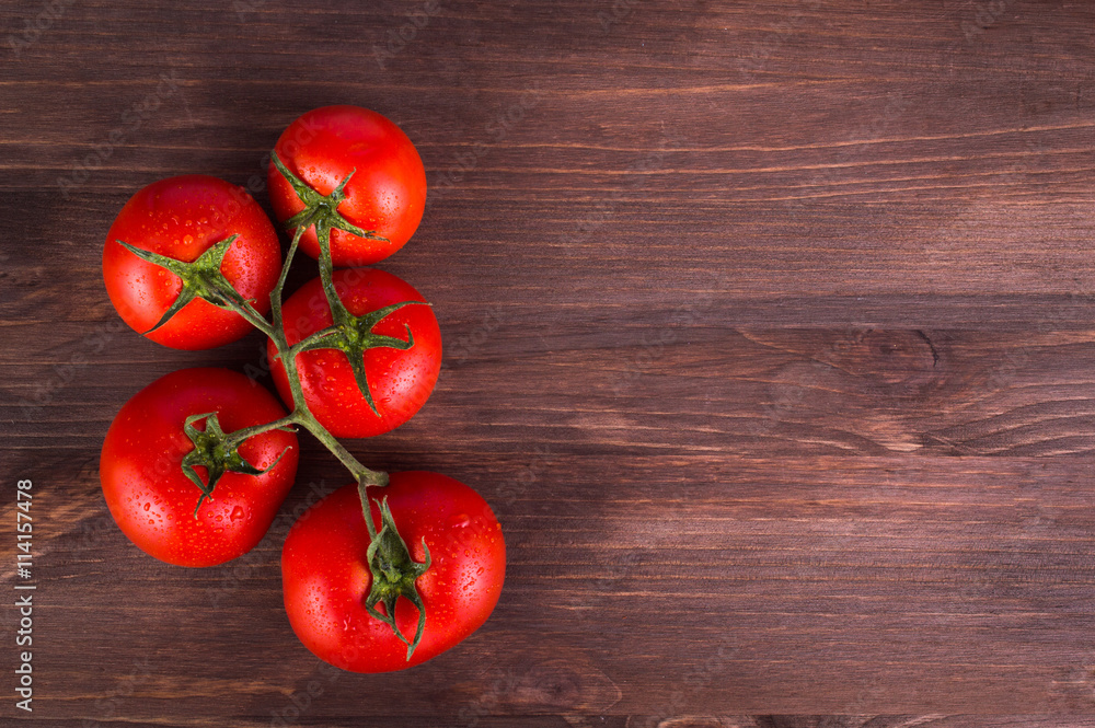 Ripe fresh tomatoes on a branch on a wooden table. Space for text. Ripe fresh tomatoes on a branch on a wooden table. Space for text.