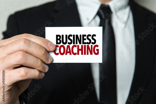 Business man holding a card with the text: Business Coaching