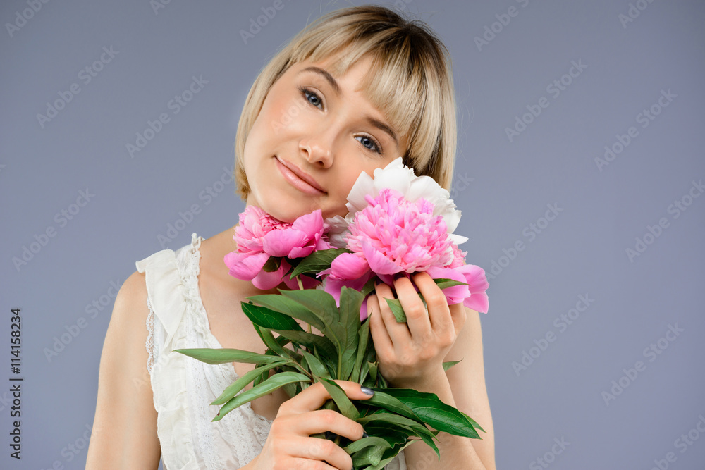 Portrait of young girl with bouquet flowers over grey backgro