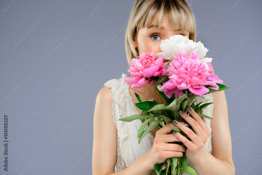 Portrait of young girl with bouquet flowers over grey backgro Portrait of young girl with bouquet flowers over grey backgro