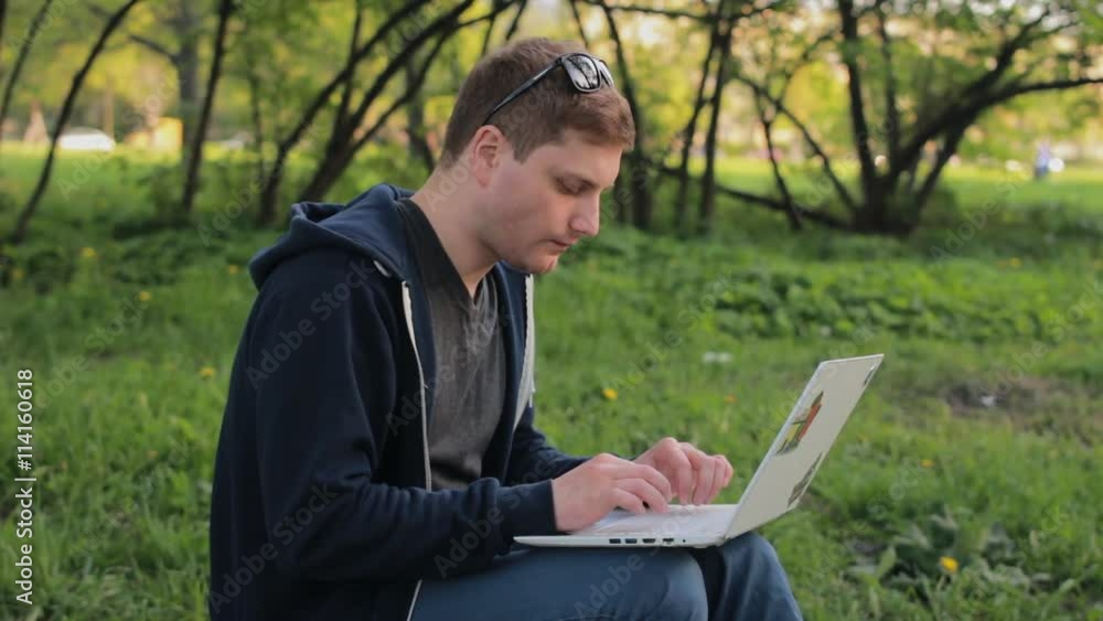Young man working on laptop in the park Young man working on laptop in the park