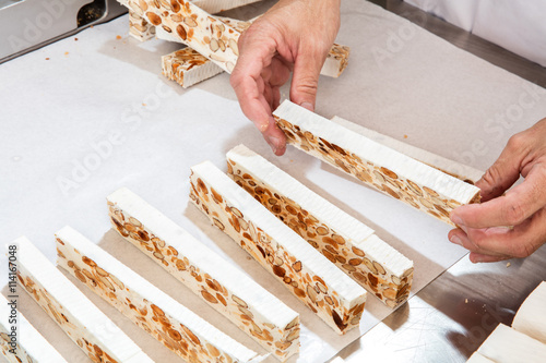 фотографія professional hands preparing freshly cut French almond nougat bars
