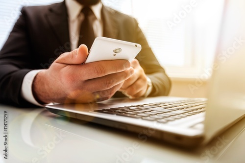 Business man hand working on phone and laptop computer.