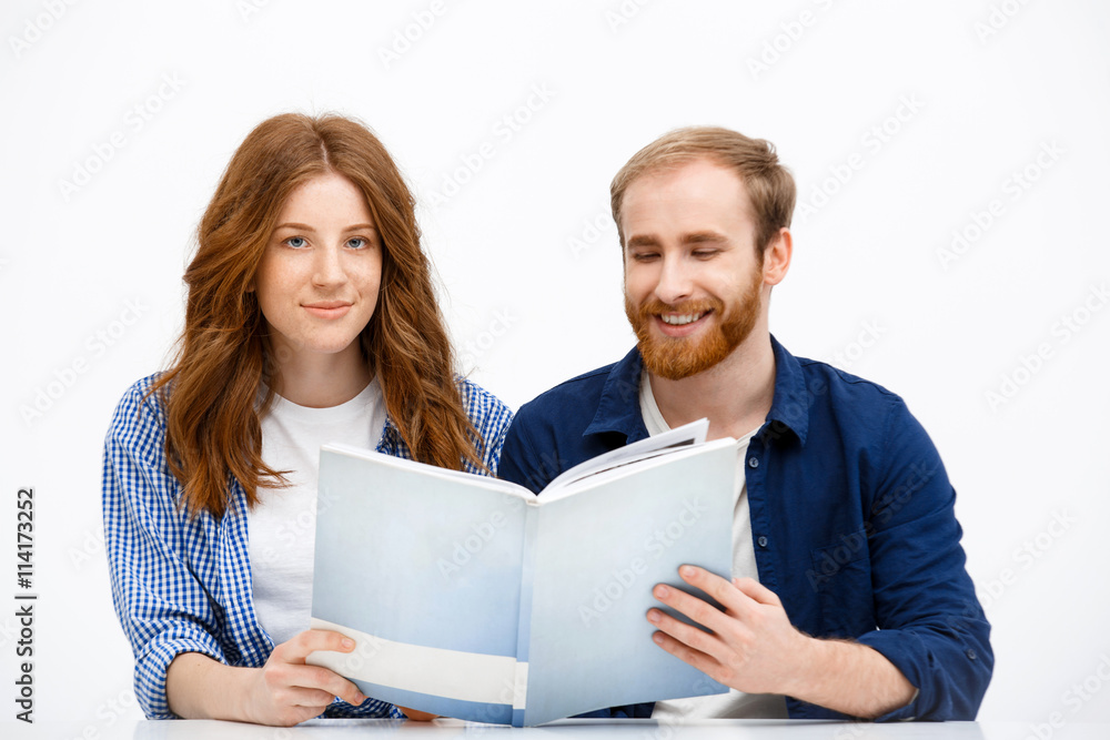 Beautiful redhead girl and boy sitting at white table. Isolated Beautiful redhead girl and boy sitting at white table. Isolated
