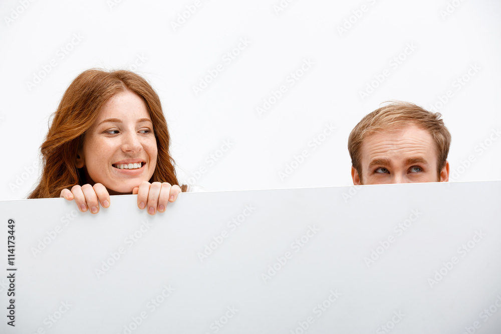 Funny redhead boy and girl hiding at white table Funny redhead boy and girl hiding at white table