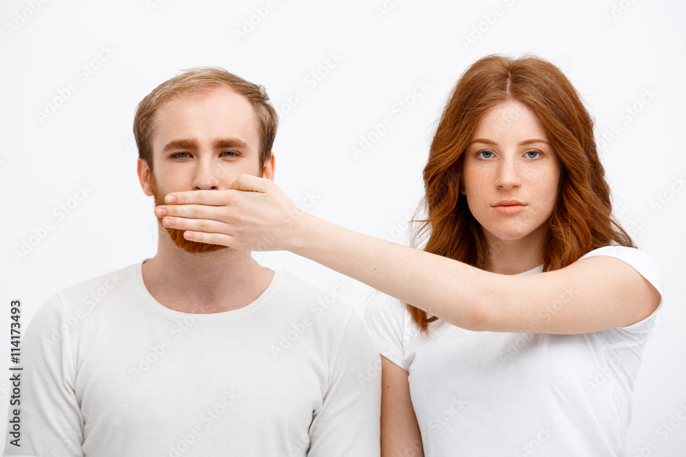 Seriously redhead girl standing over white background and hide Seriously redhead girl standing over white background and hide
