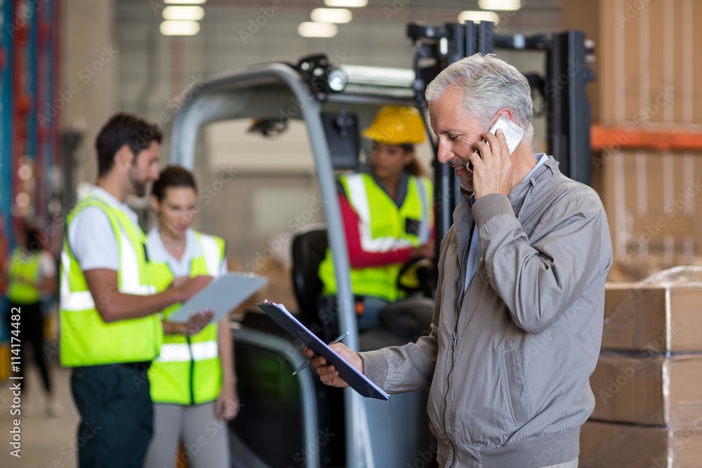 Focus on manager is talking on the phone and looking a clipboard Focus on manager is talking on the phone and looking a clipboard