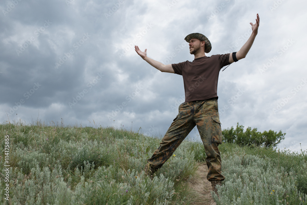 Freedom man raised hands in field at moody sky background Freedom man raised hands in field at moody sky background