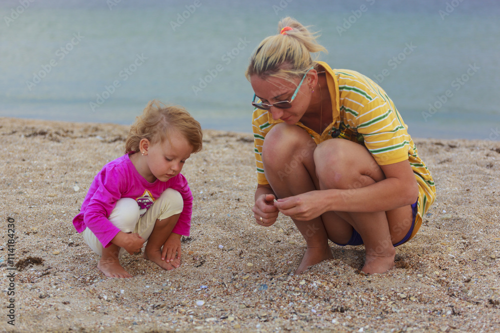 Mother and daughter sitting on the sand after sunset